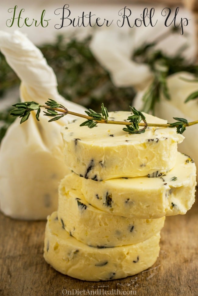 herb butter stacked on cutting board with herb sprig on top